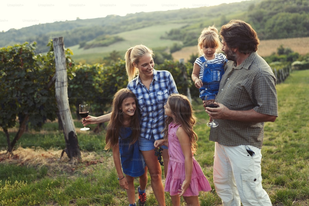 Happy wine grower family walking in vineyard together