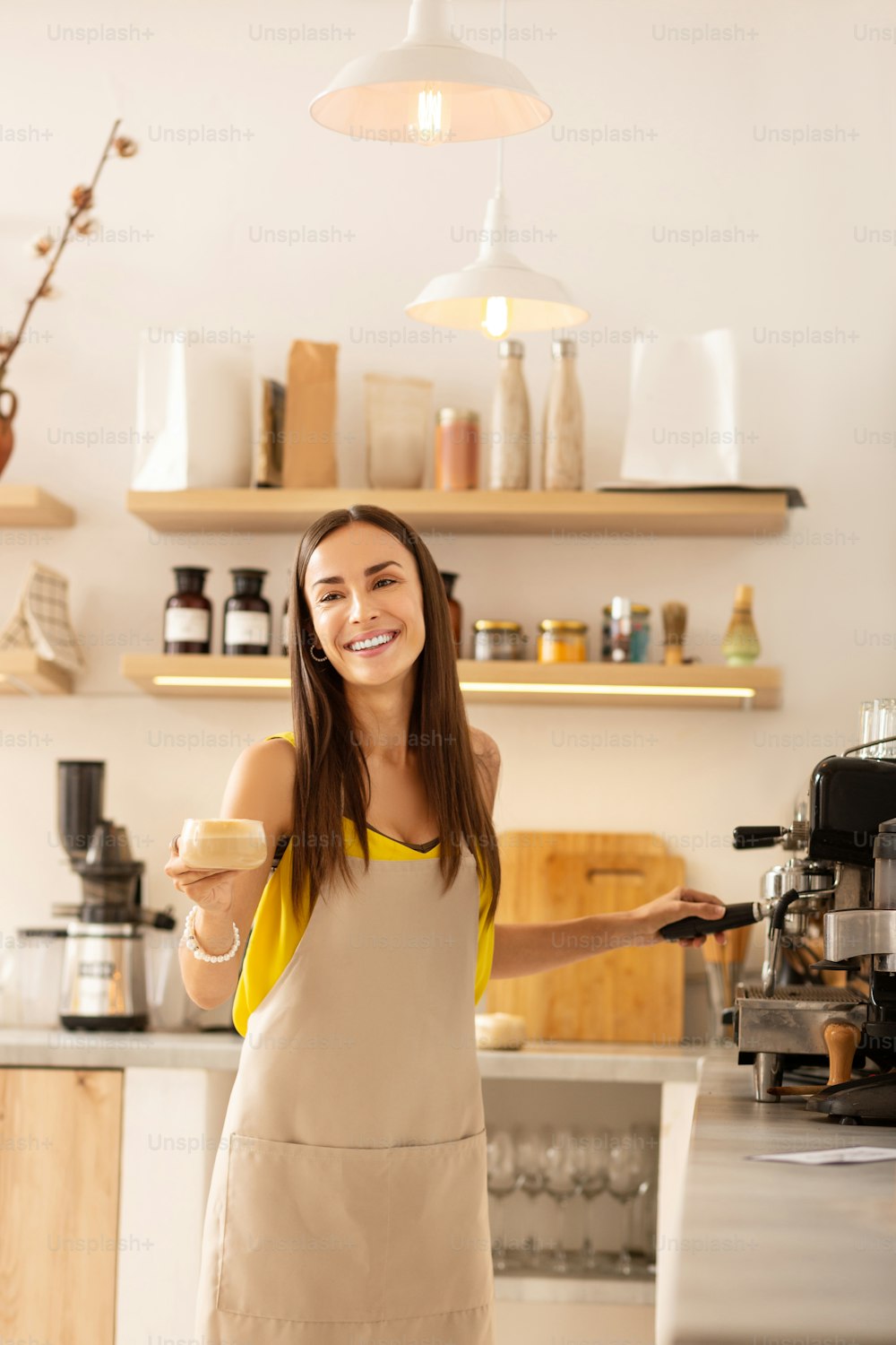 Barista smiling. Pleasant female barista smiling while talking to customer and making coffee