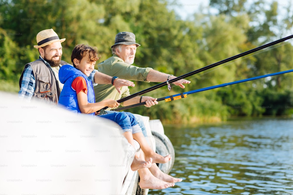 Boy feeling happy. Handsome dark-haired boy feeling happy while fishing  with father and grandfather photo – Water Image on Unsplash