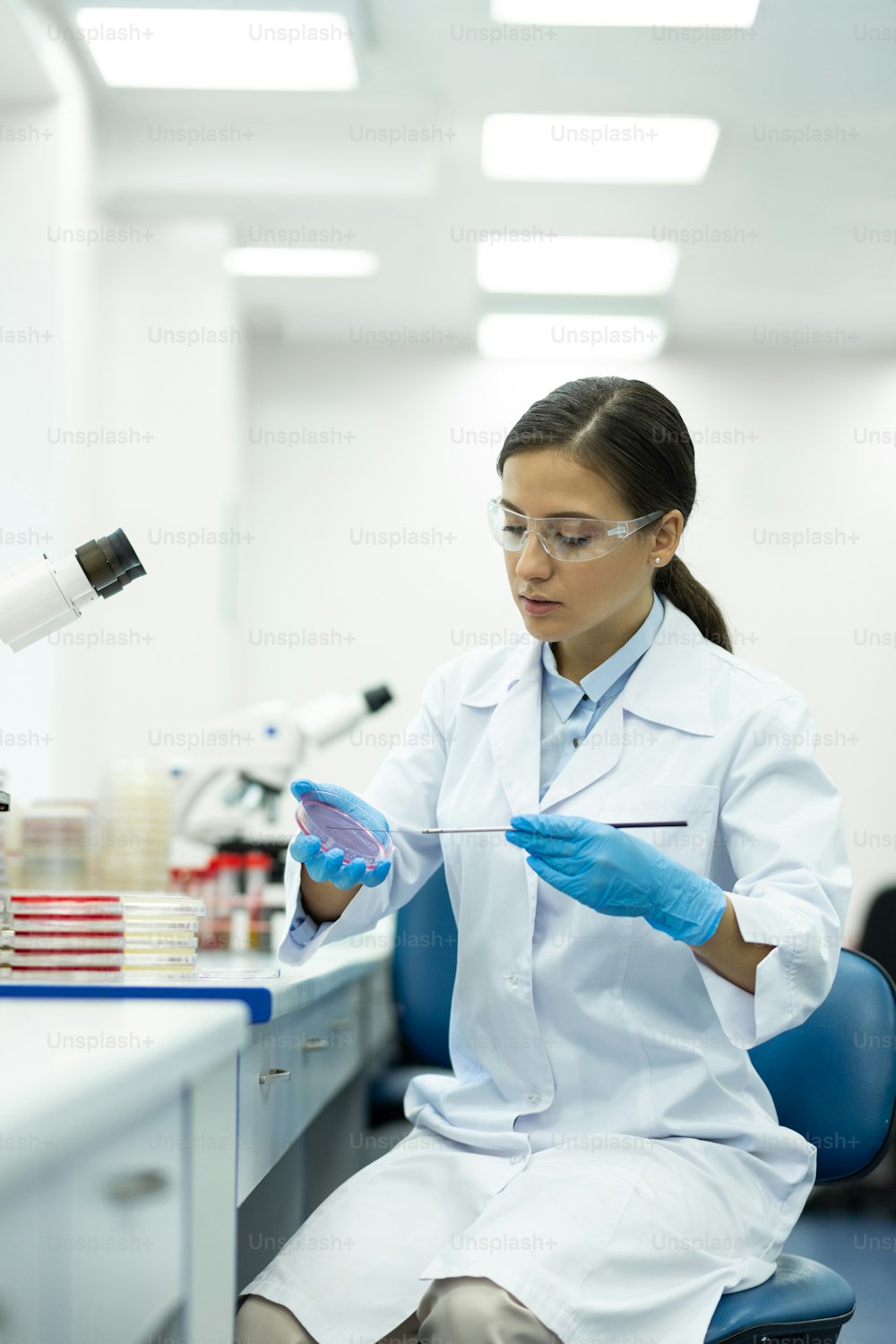Young worker. Delighted woman looking downwards while doing DNA analysis