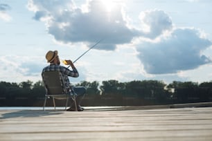 On day off. Businessman feeling relieved while fishing and drinking beer on day off