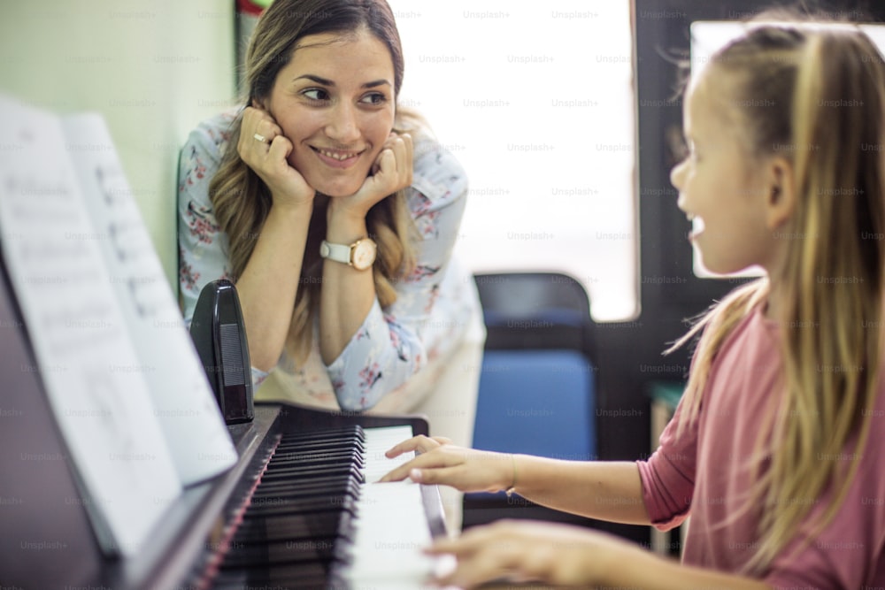 She enjoys while she plays. Child in music school with teacher.