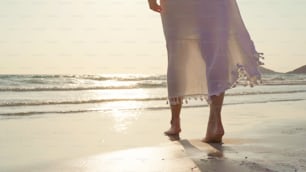 Giovane donna asiatica che cammina sulla spiaggia. Bella femmina felice relax a piedi sulla spiaggia vicino al mare quando il tramonto in serata. Le donne di stile di vita viaggiano sul concetto di spiaggia.