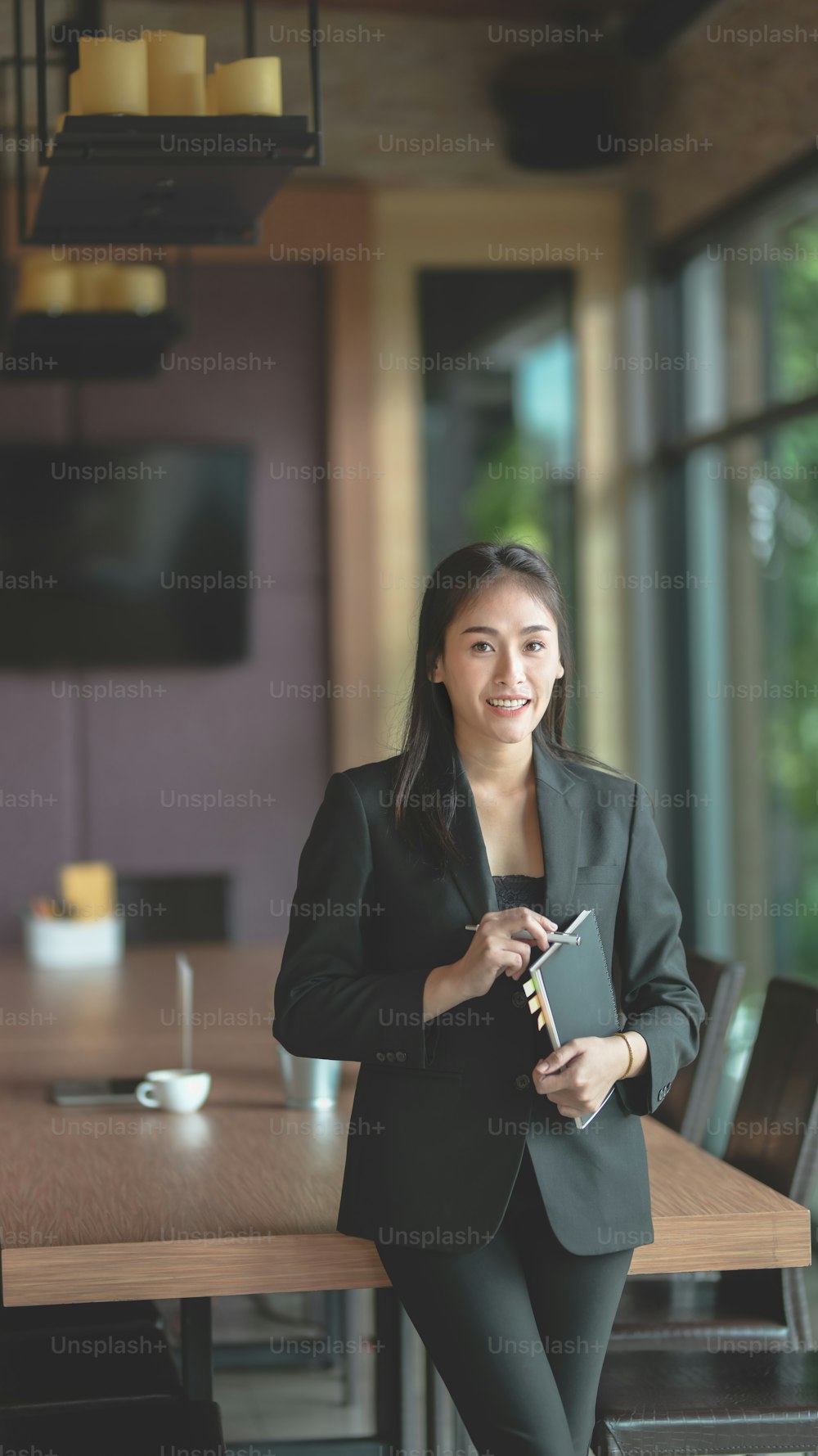 Attractive professional businesswoman standing and smiling to the camera in meeting room