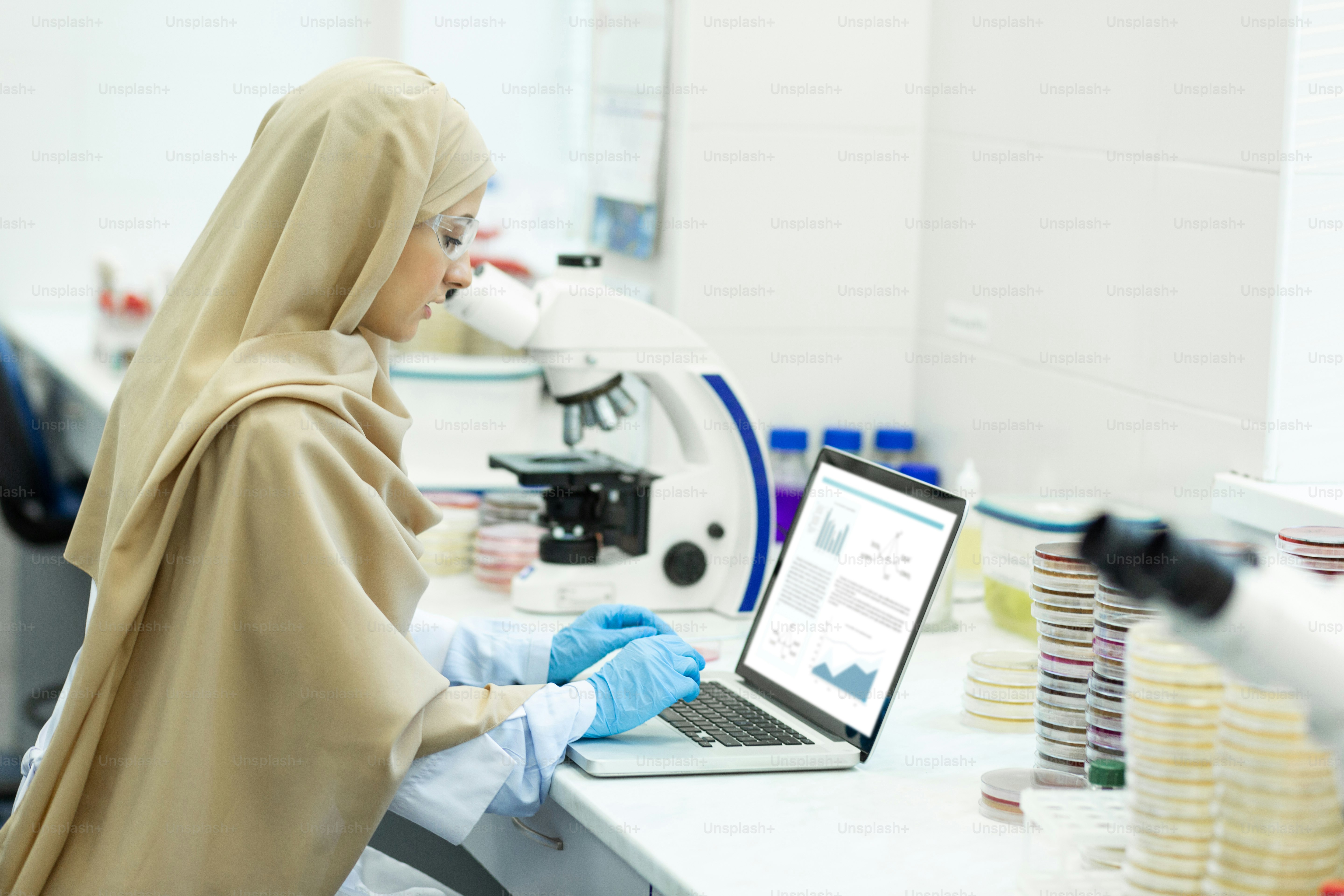 Muslim worker. Cheerful young female wearing hijab and sitting at her ...