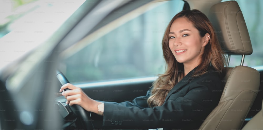 사무실로 차를 운전하는 동안 카메라에서 웃고 있는 아름다운 전문 아시아 사업가