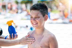 Mother applying sunblock cream on son face. Mother put sunblock cream on little boy face at beach