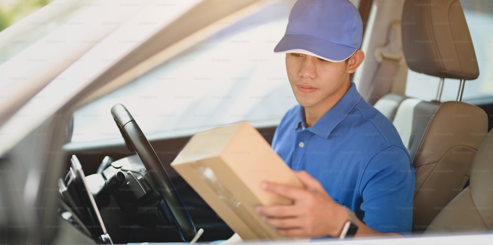 Young delivery man checking the products to customer while sitting on the car.