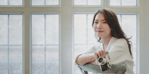 Portrait of beautiful professional photographer holding camera in modern comfortable room