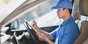 Young delivery man preparing the products to customer while sitting on the car, ready to send the products