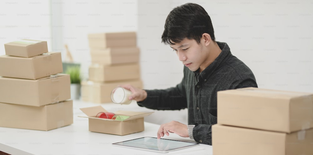 Small business concepts : Young male owner packing and selling online products at home