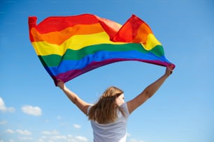 虹色の旗を振る若い女性の後ろ姿