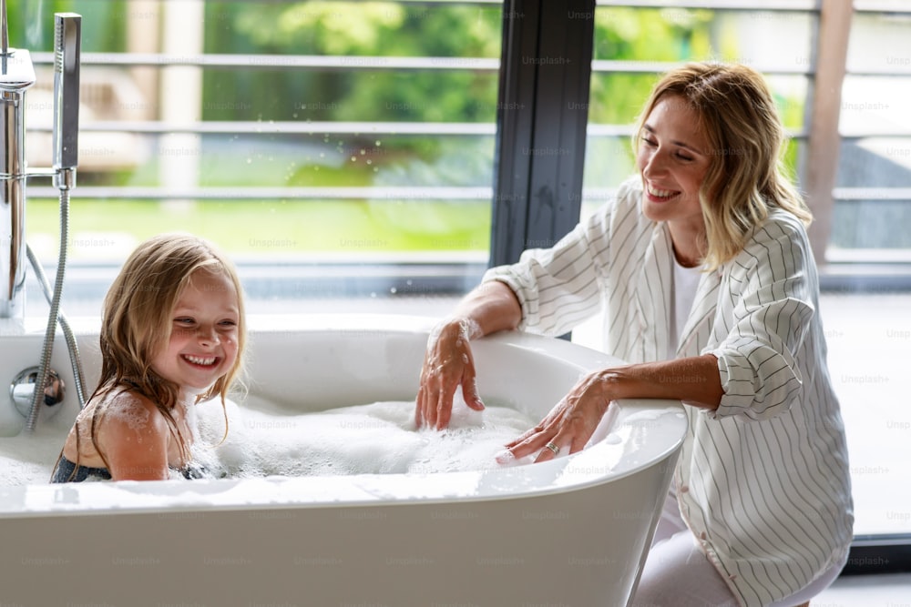 Happy mom laughing with her daughter in the bathroom stock photo