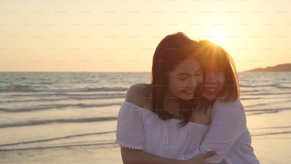 Young Asian lesbian couple kissing near beach. Beautiful women lgbt couple happy relax enjoy love and romantic moment when sunset in evening. Lifestyle lesbian couple travel on beach concept.
