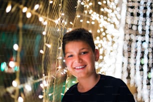 Un garçon heureux sourit dans un parc d’attractions contre des lampadaires