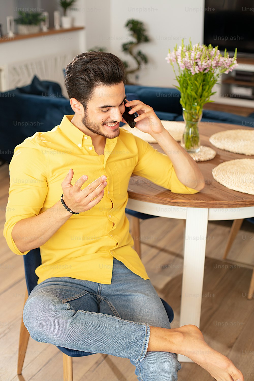 Portrait of cheerful young man relaxing at home,talking with someone by mobile phone.