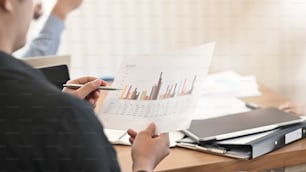 Close-up businessman analysis static finance data in meeting room.