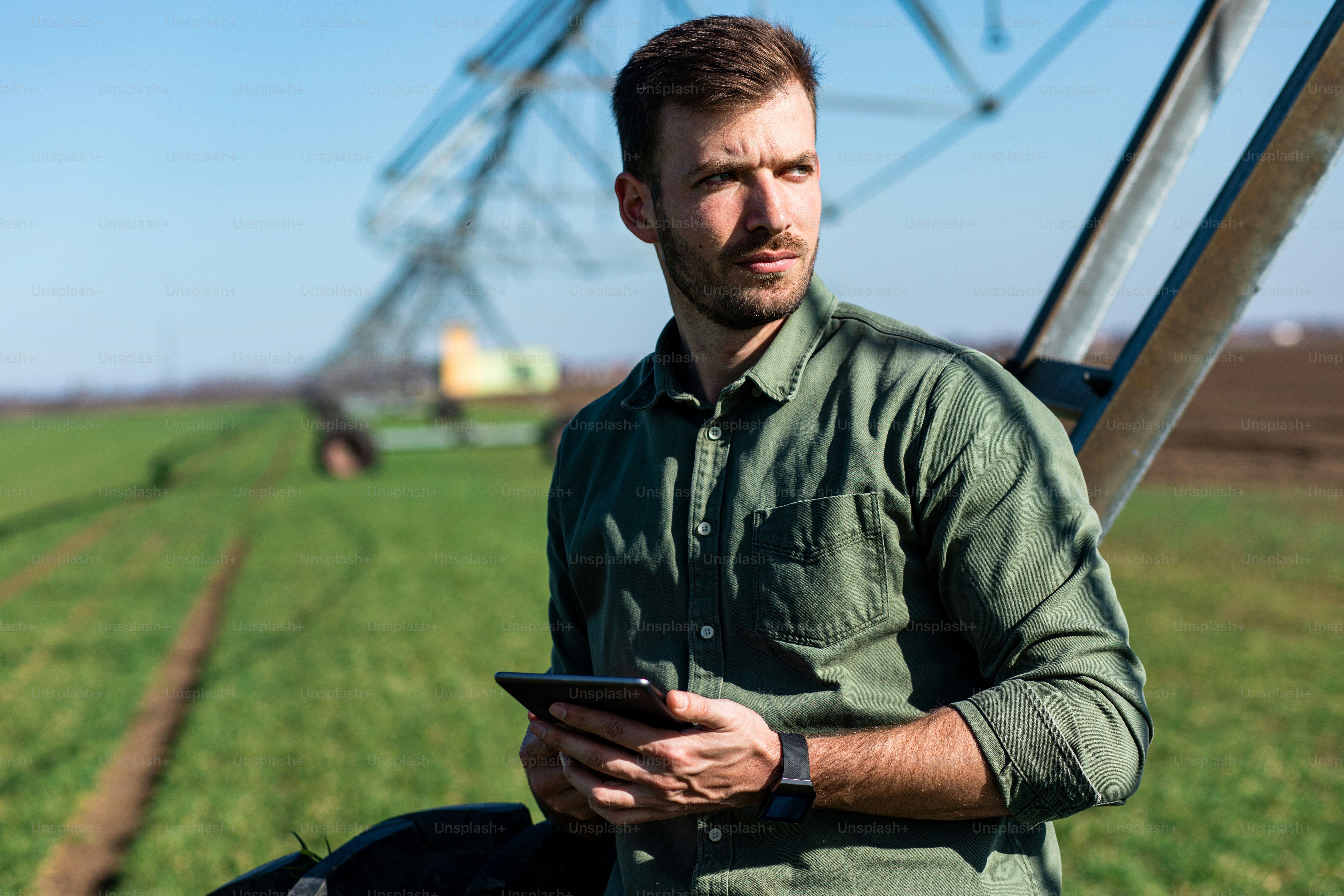 Young farmer standing in wheat field and setup irrigation system on tablet.