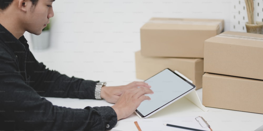 Young male small business owner checking orders and preparing the products for customers at home