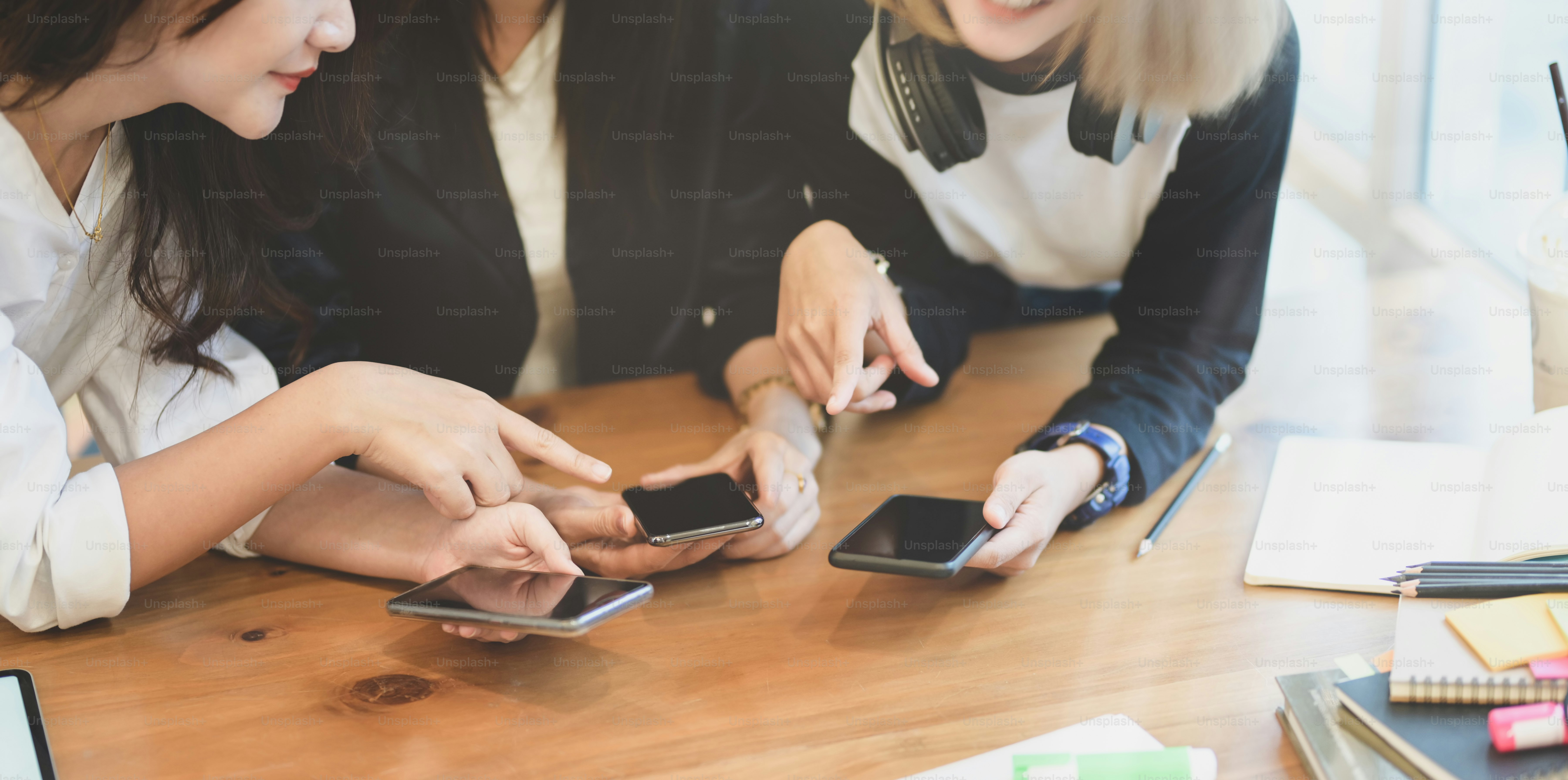 Female freelancers sharing information on smartphone to other team members.