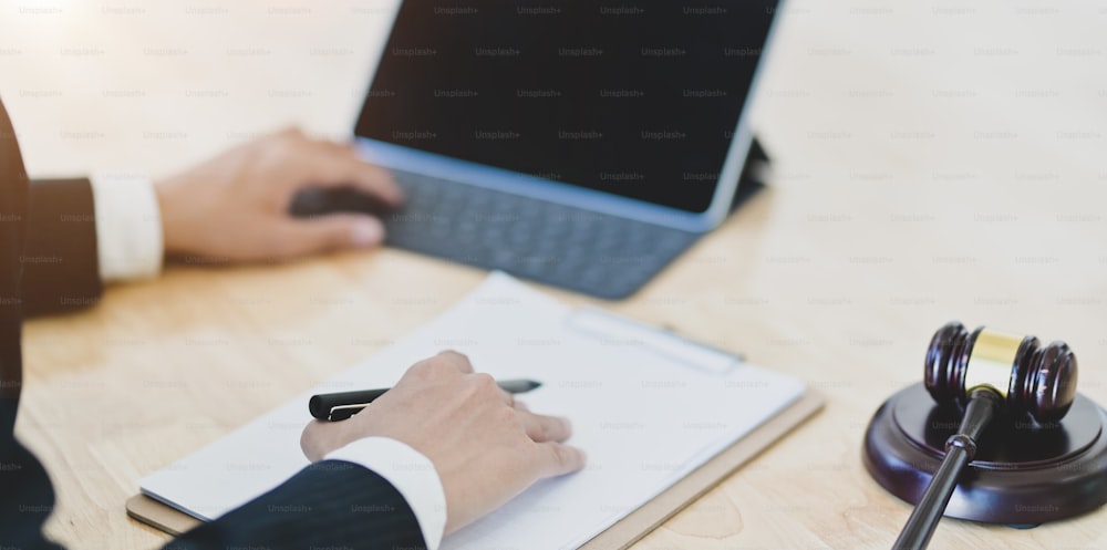 Close-up view of male legal advisor working on a laptop and providing legal document for his client