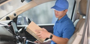 Young delivery man checking orders while preparing the products to customers