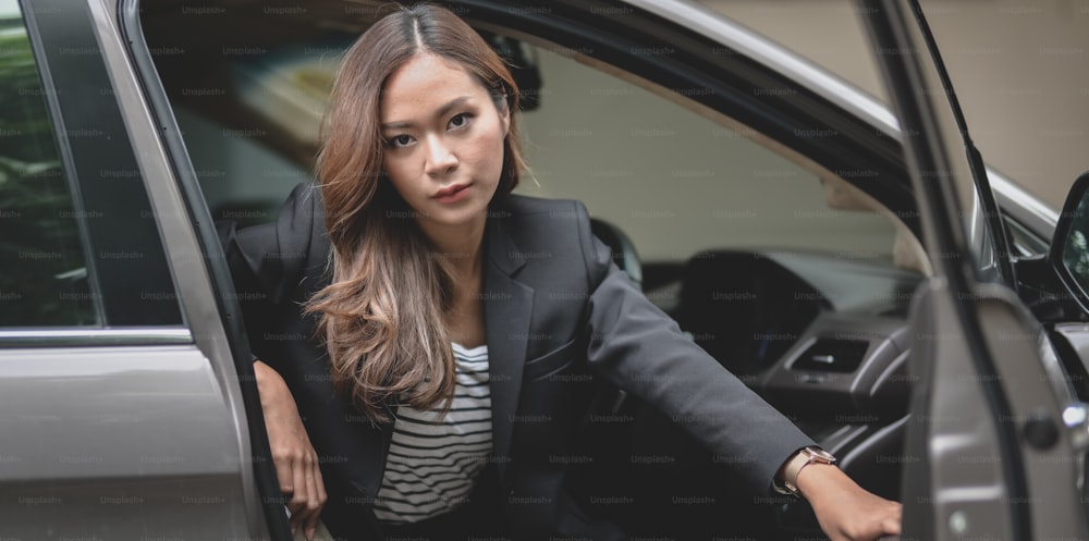 Beautiful businesswoman getting out of the modern luxury car.