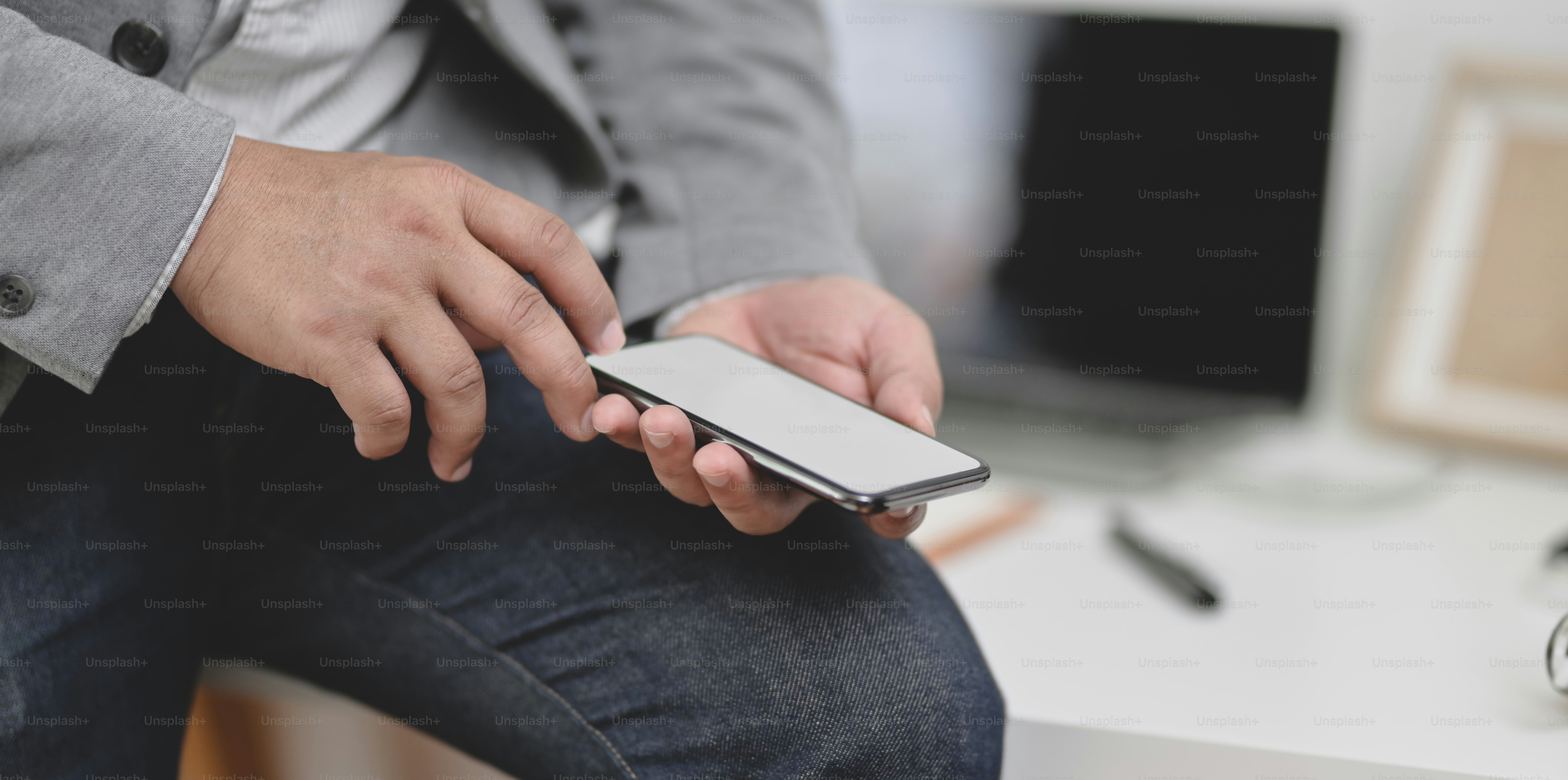 Vue rapprochée d’un homme d’affaires tenant un smartphone à écran vide dans son bureau moderne