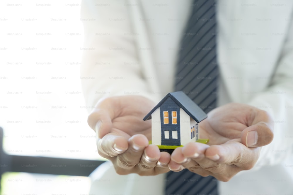 Business man hand hold the house model saving small house. House insurance.