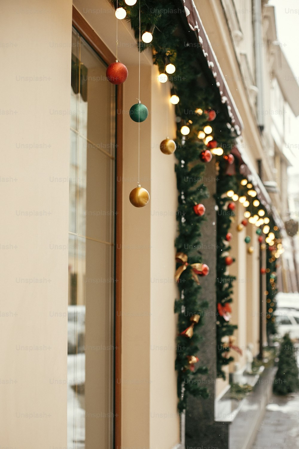Weihnachtliche Straßendekoration. Stilvolle Weihnachtstannenzweige mit goldenen Lichtern und bunten festlichen Kugeln im Schaufenster des Weihnachtsmarktes in der Stadtstraße. Platz für Text.