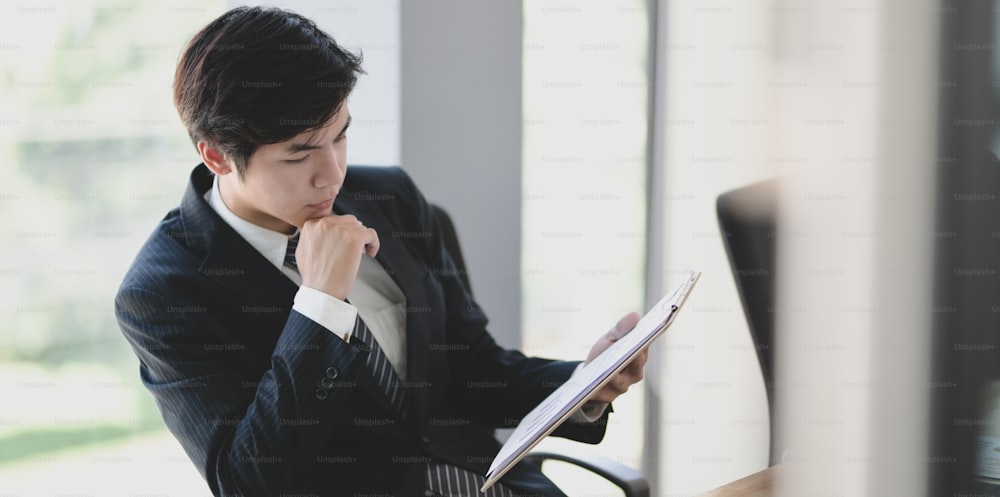 Handsome young businessman checking the data on the document preparing before meeting