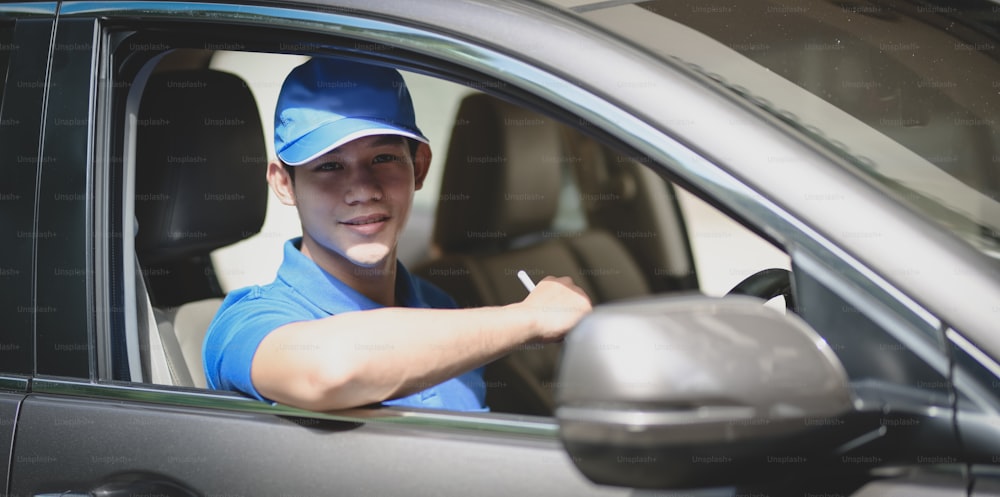 Young delivery man preparing the products to customer while sitting on the car, ready to send the products
