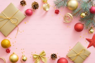 Composizione flatlay per le vacanze di Natale su sfondo rosa pastello con spazio di copia. Vista dall'alto rami di abete di Natale, palline rosse e dorate, confezione regalo, pone coni. Mockup di biglietto di auguri di Natale.