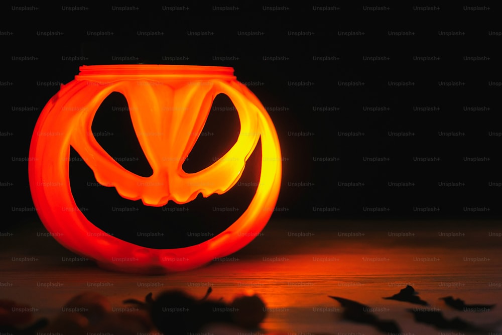 Happy Halloween. Glowing Jack-o-lantern face in dark. Spooky atmospheric jack o lantern glowing pumpkin bucket on black background. Trick or treat. Copy space