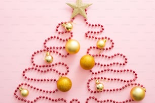 Christmas tree made of red garland, golden bauble and star. Flat lay, top view, overhead. Xmas creative layout. Christmas, winter holiday, New Year concept.