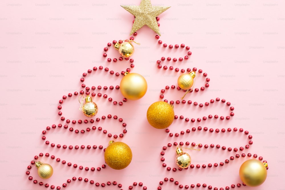 赤い花輪、金色の安物、星で作られたクリスマスツリー。フラットレイ、上面図、オーバーヘッド。クリスマスのクリエイティブなレイアウト。クリスマス、冬休み、新年のコンセプト。