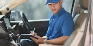 Young delivery man preparing the products to customer while sitting on the car, ready to send the products