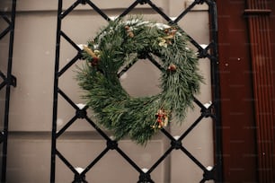Christmas street decor. Stylish christmas rustic wreath with pine cones and berries at front doors of store at holiday market in city street. Space for text. Rustic decoration