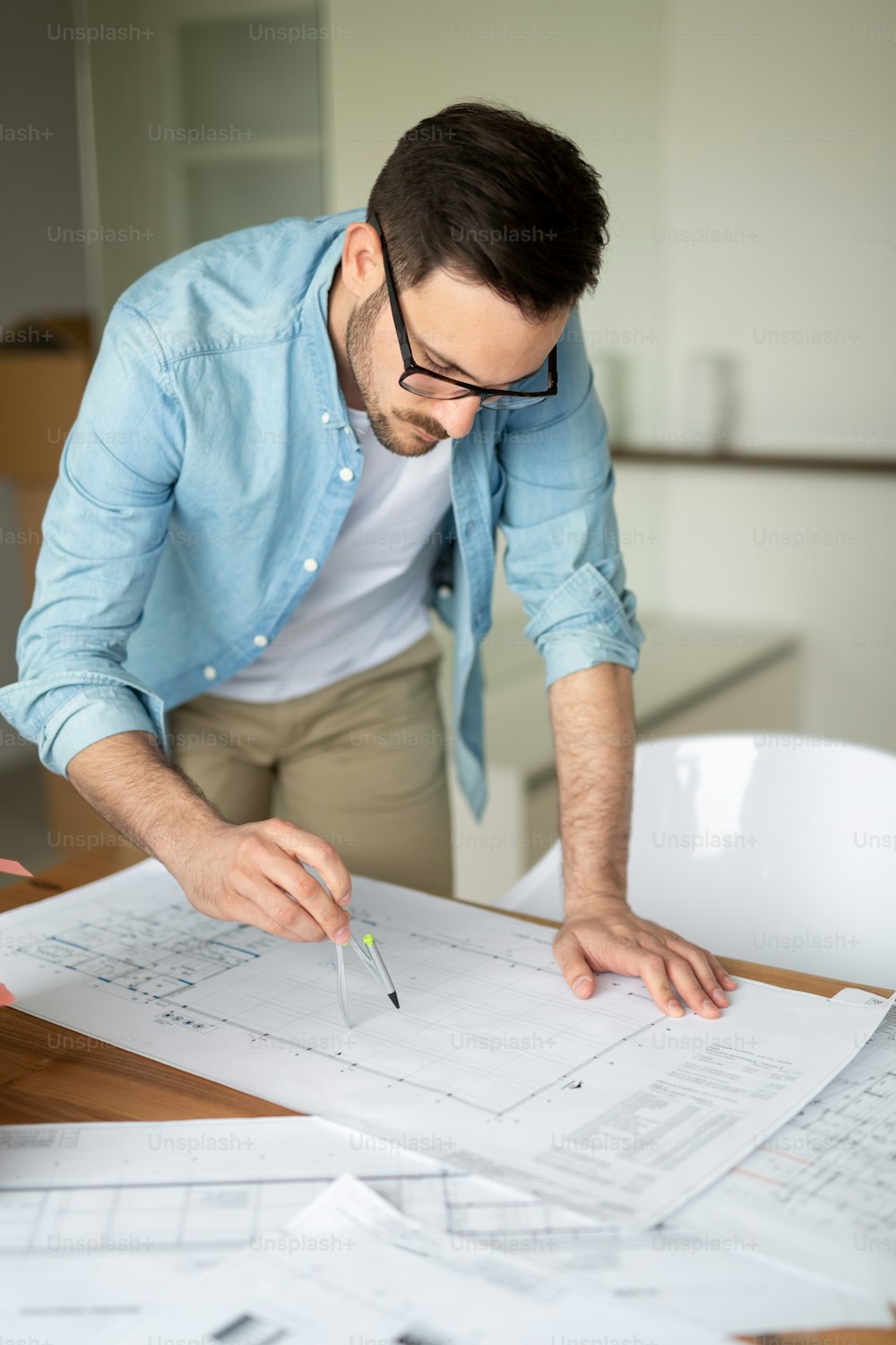 Portrait of adult architect working on plans and blueprints in office