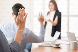 Les gens d’affaires lèvent la main lors d’une conférence de réunion pour répondre à une question et présenter leur opinion.