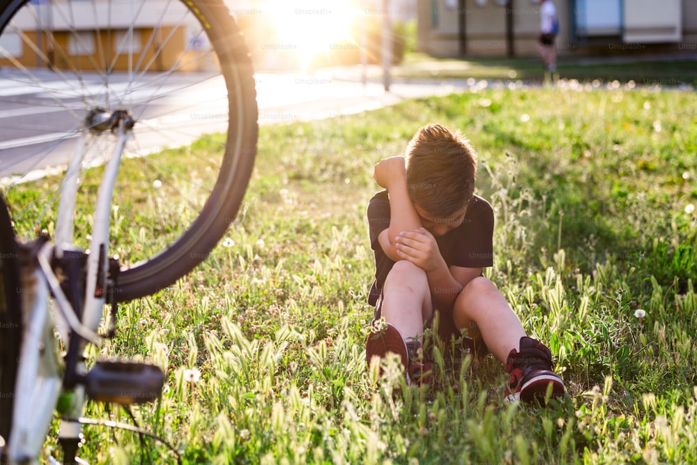 Adolescente Hay una lesión en la rodilla, ya que la bicicleta se cae mientras conduce. El niño se lastima la pierna después de caerse de la bicicleta. El niño está aprendiendo a andar en bicicleta.