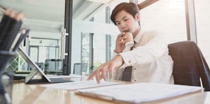 Young professional businessman working on his project while drinking a cup of coffee in his modern office