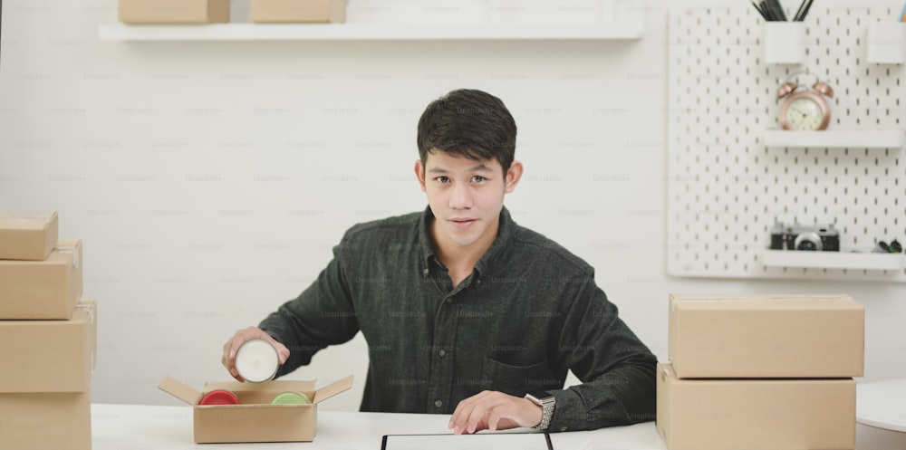 Young male small business owner checking orders and preparing the products for customers at home