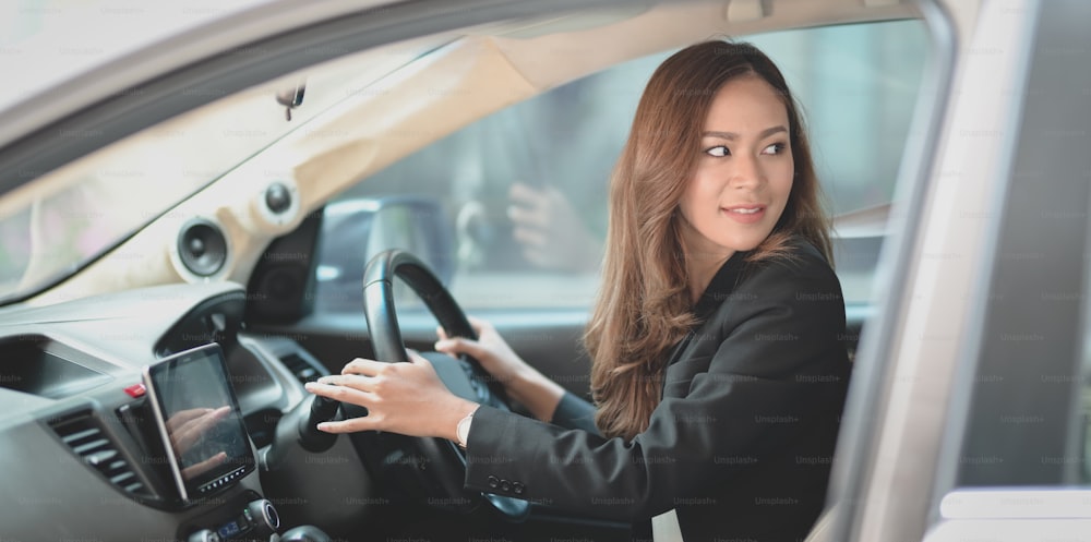 Bella donna d'affari che guida l'auto moderna mentre si dirige verso l'ufficio.