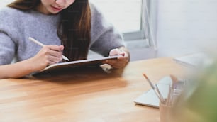 Mujer joven usando bolígrafo en tableta digital.