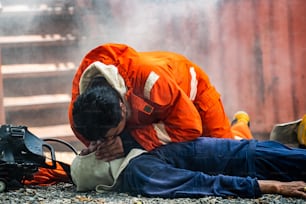 Tiro médio de bombeiro em traje de incêndio em serviço de resgate de segurança ajuda a parar de respirar homem de ataque cardíaco dentro de instalações em chamas por RCP de emergência de primeiros socorros. Conceito de segurança, resgate e saúde.