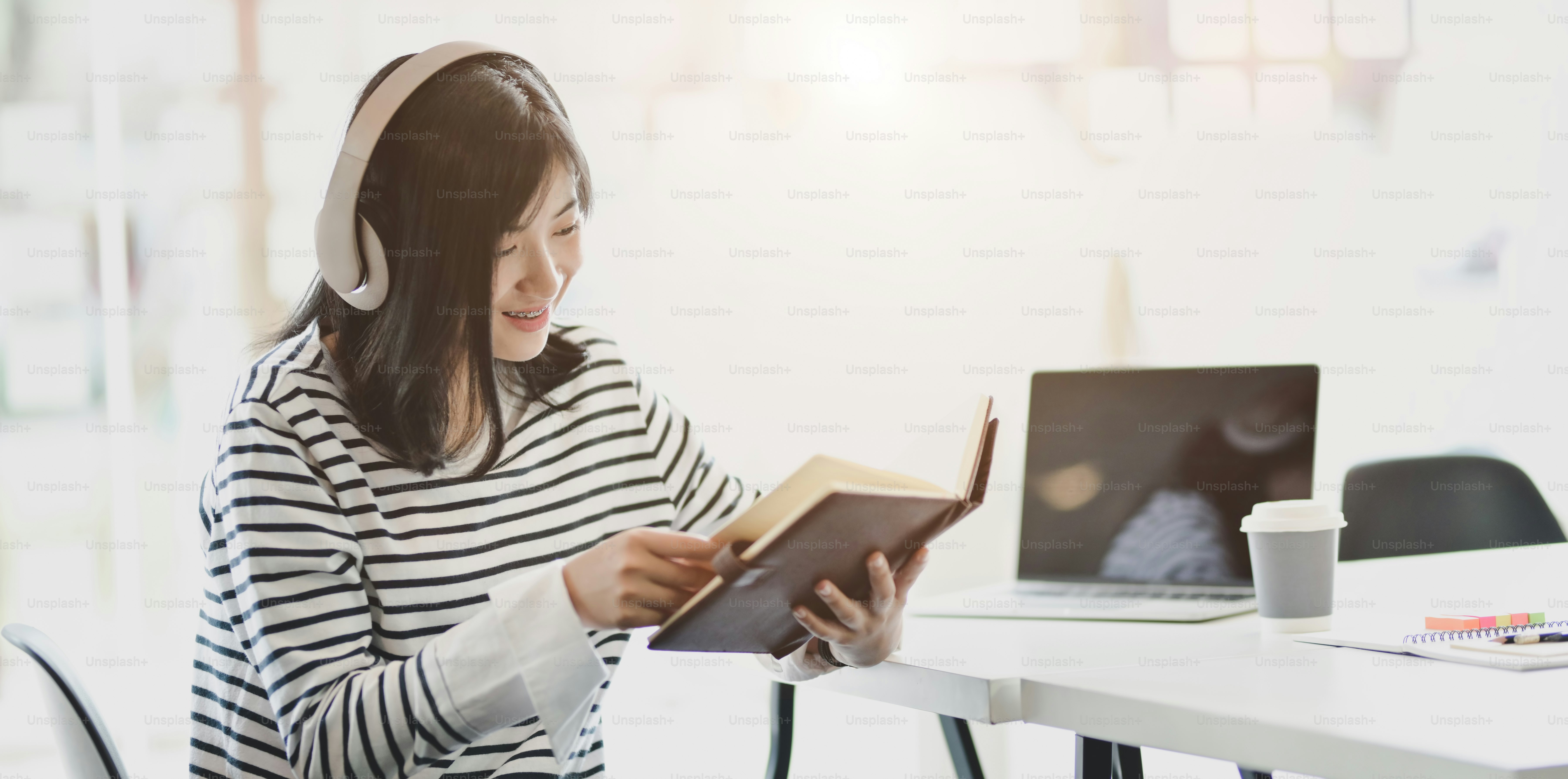 Junges, fröhliches Mädchen, das Romane liest und in ihrer Freizeit zu Hause Musik hört