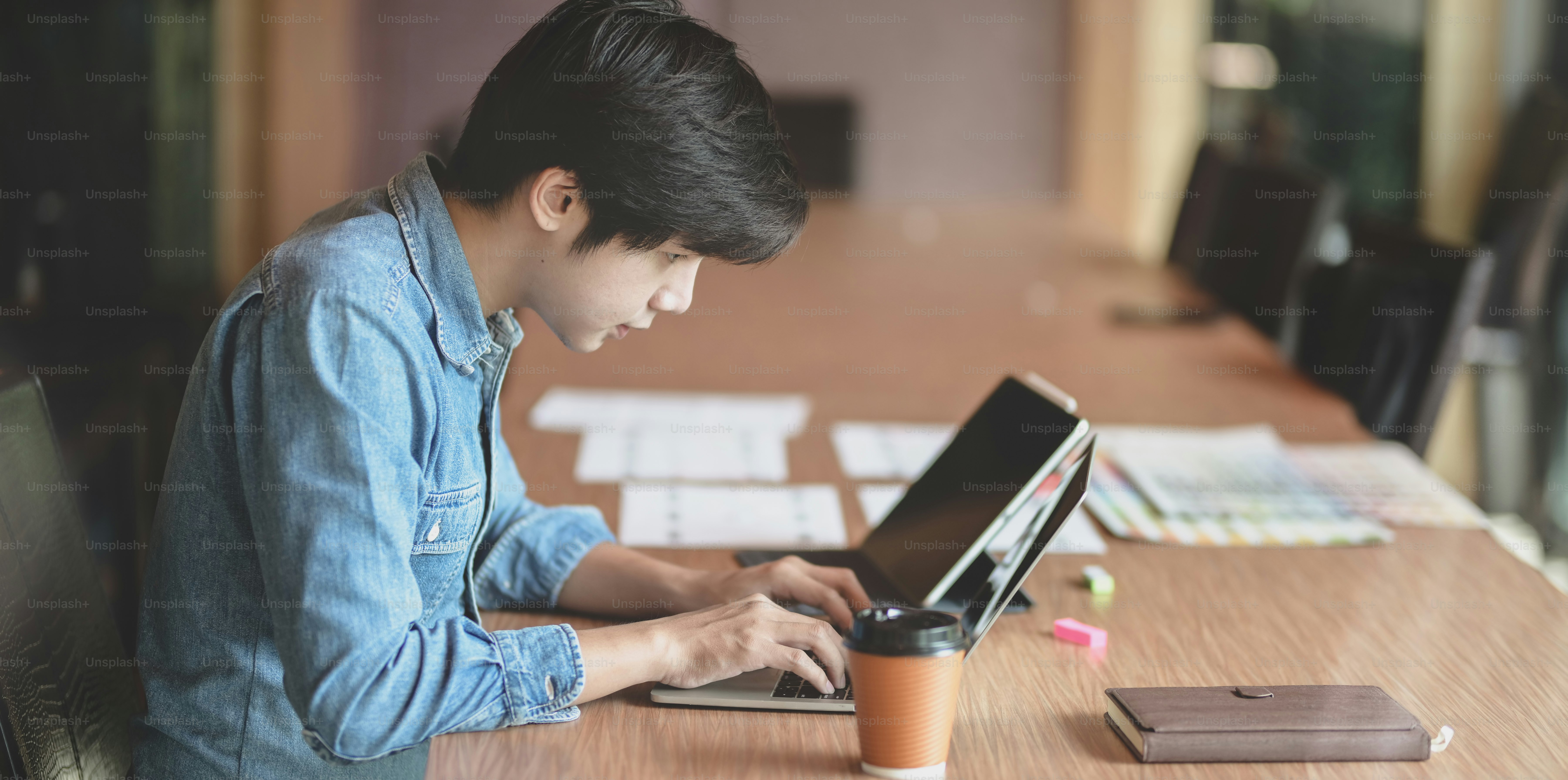 Desainer web UX pria profesional yang mengerjakan proyek template smartphone barunya sambil menggunakan komputer laptop