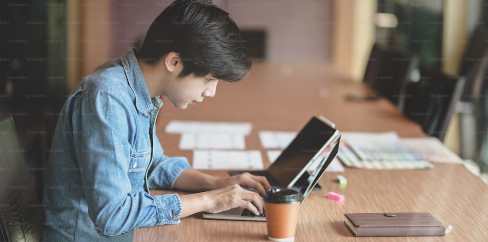 Professional male UX web designer working on his new smartphone templates project while using laptop computer