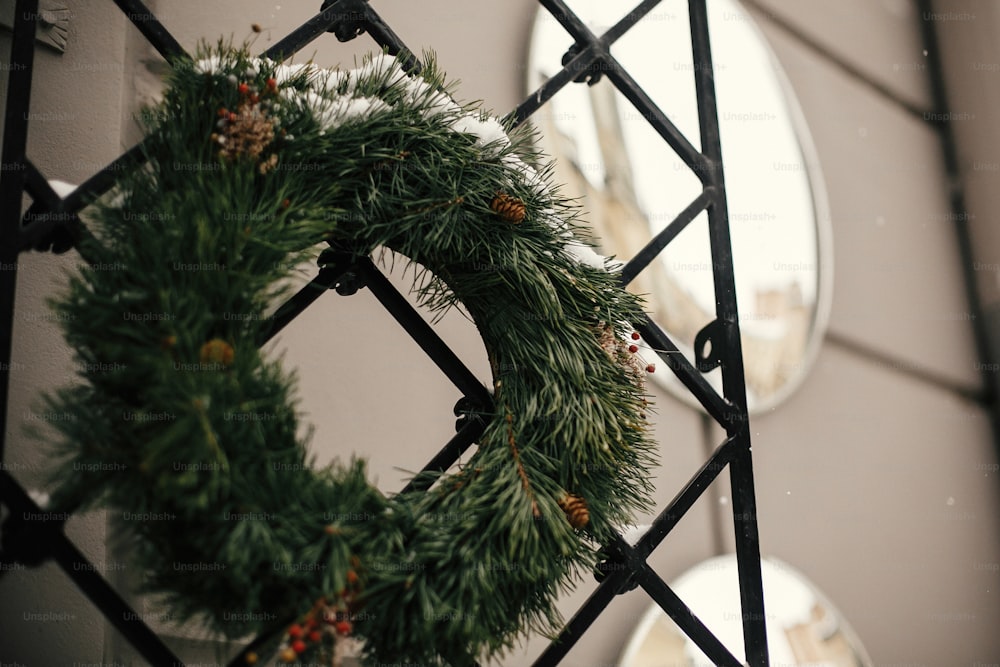 クリスマスの通りの装飾。松ぼっくりとベリーが飾られたスタイリッシュなクリスマスの素朴なリースが、街の通りにあるホリデーマーケットの店の正面玄関にあります。テキスト用のスペース。素朴な装飾